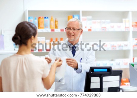 medicine, pharmaceutics, healthcare and people concept - senior apothecary with drug and female customer at pharmacy Royalty-Free Stock Photo #774929803
