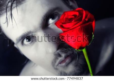 young man holding a red rose on a black background