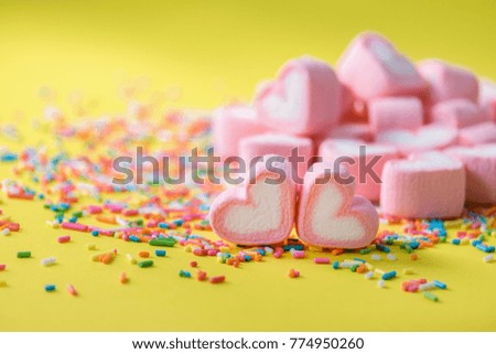 Heart shape of pink marshmallow on sprinkles on green background with copy space. Concept for valentine's day love celebration.