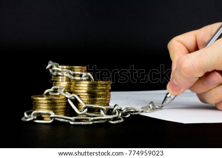 money bound by a chain gold coins signing the document with a pen on a black background selective focus