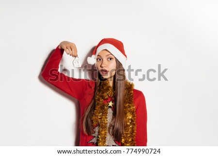 cute young girl in festive clothes waiting for the new year and Christmas, holding in her hand a white fur-tree toy