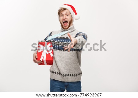 Holiday Concept - Young beard man holding christmas gift and throwing money to camera.