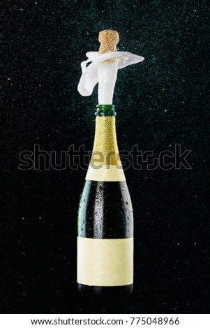 Champagne bottle with popping cork and splash isolated on black.