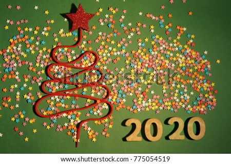 Christmas Tree constructed from a lot colorful confetti, lace and candy stars toy on green paper texture background. Empty copy space for inscription. Idea of merry new year 2020 holiday