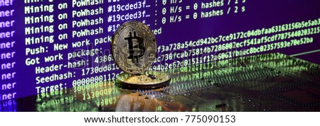 Two bitcoins lies on a videocard surface with background of screen display of cryptocurrency mining by using the GPUs