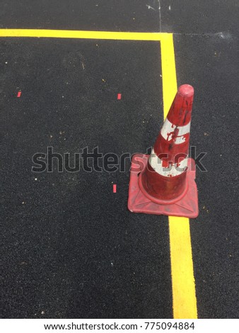 Red traffic cone with the yellow line are on the cement road