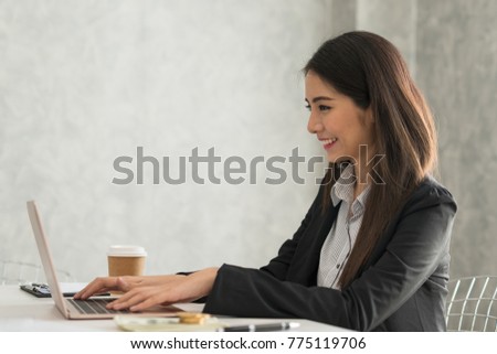 Beautiful asian young businesswoman working on laptop in her workstation