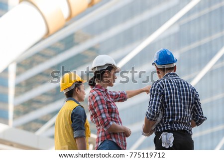 Asian engineers group consult construction on site building working while holding blueprint paper. in city background. teamwork concept