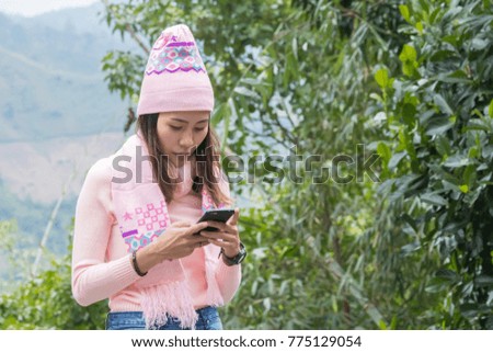 Asian women with pink hat playing mobile phone. In the park