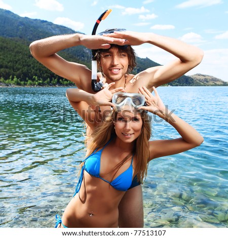 Happy young couple with snorkelling gear standing on a sea beach.