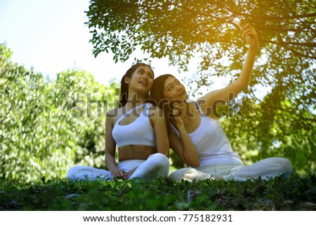 Young women wear white clothes making selfie with happy face by mobile phone in the park