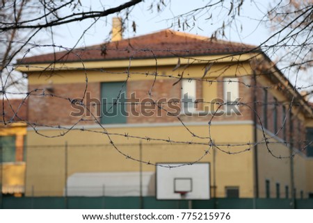 external view of a reformatory with a basketball court and barbed wire and the prison in background Royalty-Free Stock Photo #775215976