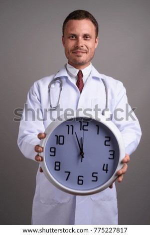 Studio shot of handsome man doctor against gray background