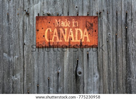 Rusty metal sign on wooden wall with the phrase: Made in Canada.
