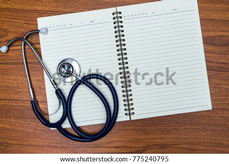 Stethoscope and notebook on bright wood table top view with copy space, health and concept.