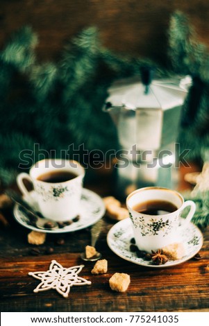 Two cups of espresso with pieces of cane sugar and Italian coffee maker on wooden table.