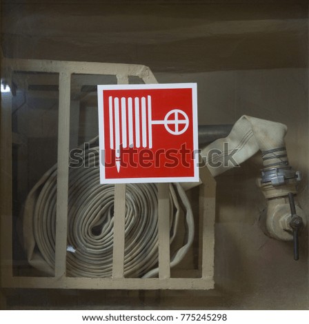 Old fire hose with fire hose sign on the glass