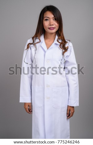 Studio shot of Asian woman doctor against gray background