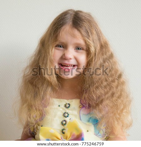 Lovely portrait of a little child. Beautiful smiling little girl in a beautiful dress with long blond curly hair. Little happy princess. Smiling kid.
