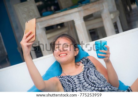 young sweet and pretty Asian Chinese woman sitting at beach holiday resort taking selfie picture on mobile phone happy and excited for internet social media in Summer holiday trip
