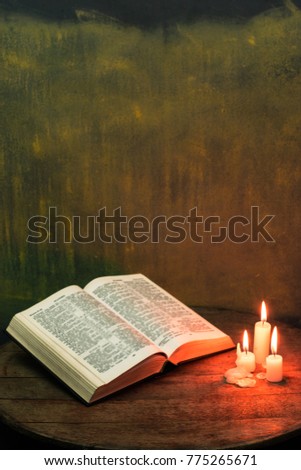 Bible and candle on a old round table.  Beautiful gold background.Religion concept.