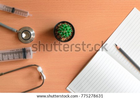 notepad, cactus with stethoscope and pencil on wood board background.using wallpaper for education, business photo.Take note of the product for book with paper object, concept or copy space.