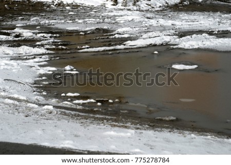 Wet road, pavement covered with beautiful and clean white snow. Autumn and winter holiday background