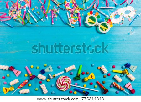 Colorful birthday party supplies on blue wooden background, top niew and copy space