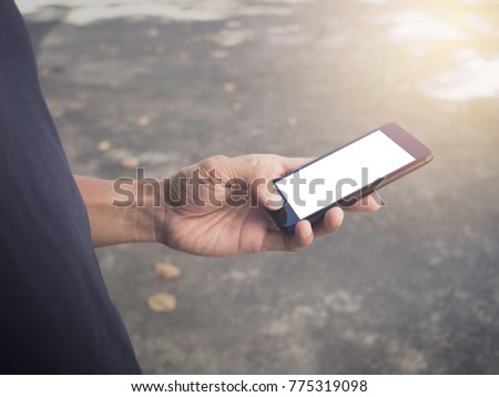 Image of man's hands are holding and touch a black cell phone with white blank screen that can put any idea and concept in this space.