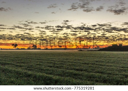 Country windmill surrounded by colourful sunrise and harvested field