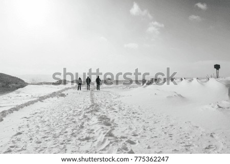 in cold winter Iceland on white snow there are 3 people in warm clothes