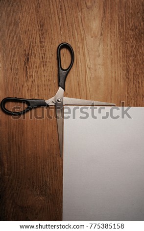 black scissors lie on wooden table neaer empty paper page background. using as background tools concept