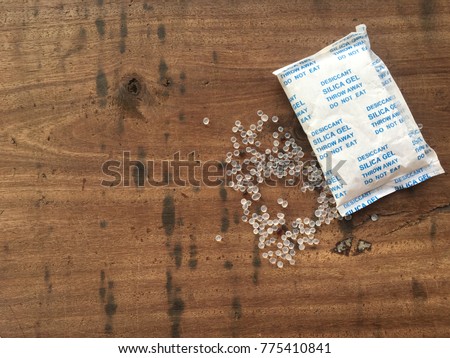 Desiccant silica gel on wood, used for moisture protection in the food industry, on packaging has the label clearly labeled "Desiccant, Silica gel, Throw Away, Do not eat"