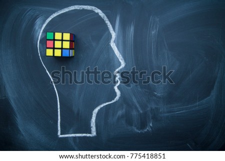 Develope creative thinking. A head drawn with a chalk on a blackboard and a Rubik's Cube. Space for your text or produst display. Royalty-Free Stock Photo #775418851