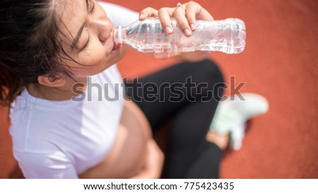 Pregnant women are drinking clean water after she loses sweat from exercise. Pregnant women with exercise and she are taking care of their health.close up image. 
