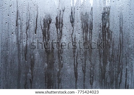 Rain drops on window glasses surface with sky cloudy background or texture grey frames abstract water of rainy day on black and white city at night silhouette Natural Pattern Royalty-Free Stock Photo #775424023