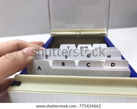 One hand try to find business name card on the business card holder box from the alphabet index