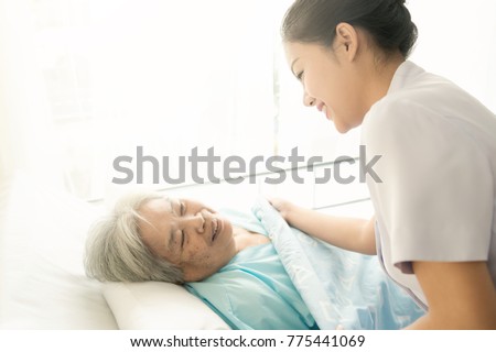Nurse with patient. Routine health check and putting elderly patient to bed. Female nurse with senior chinese woman. Royalty-Free Stock Photo #775441069