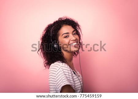 Beautiful woman with afro hair listining to music and dancing on