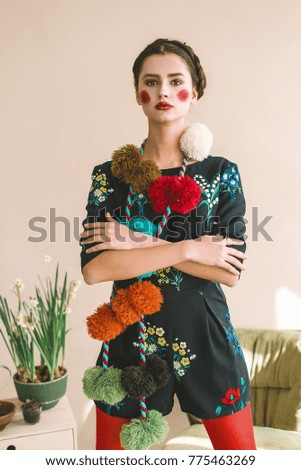 Fashionable beautiful brunette happy girl in a jumpsuit with floral embroidery with color makeup: red cheeks and lips. Granny chic style. Retouched portrait.Conceptual photo