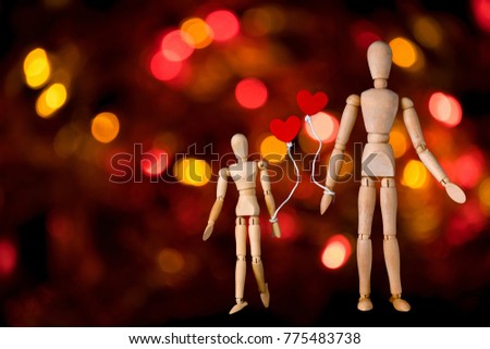 Wooden man figure holding red heart balloon. Wooden human dummy on a red bokeh lights background with copy space for your text. Concept for valentine's day celebration or couple of love.