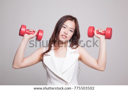 Exhausted Asian woman with dumbbells on gray background