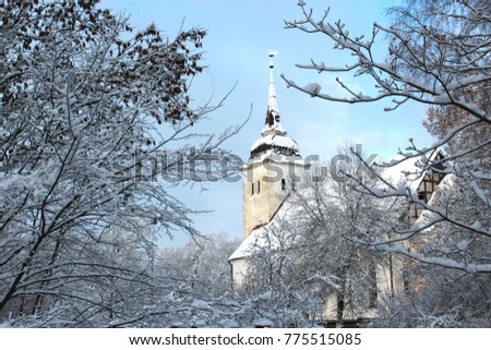 Landscape with church covered with snow. Sunny morning with blue sky and frozen trees. Beautiful winter scene with frozen branches.