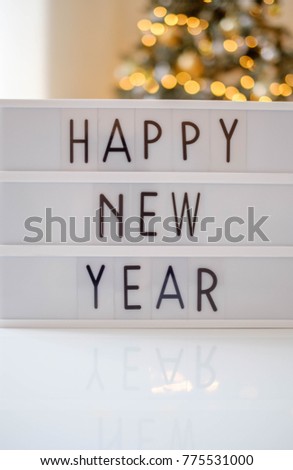 lightbox with text happy new year and led lights blurred bokeh background, christmas decoration