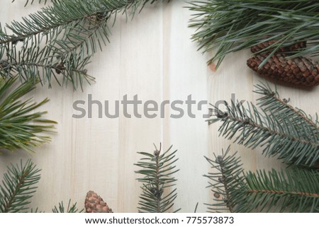 Christmas fir tree frame on natural wooden background with cone