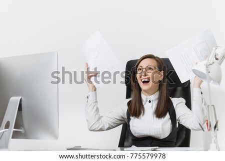 Pretty angry business woman in suit sitting at the desk with documents, working at computer with modern monitor in light office, swearing and screaming, resolving issues, on white background.