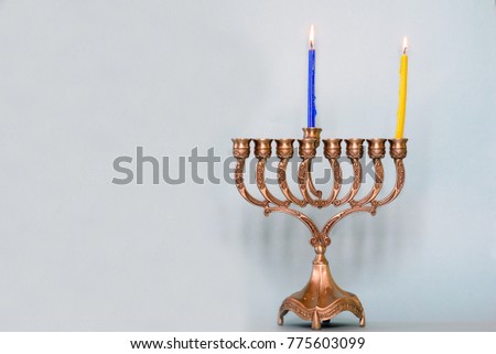 First day of Hanukkah with burning Hanukkah colorful candles in Menorah (traditional Candelabra) .Chanukkah-jewish holiday. Each night, another candle is added. Copy space for text.