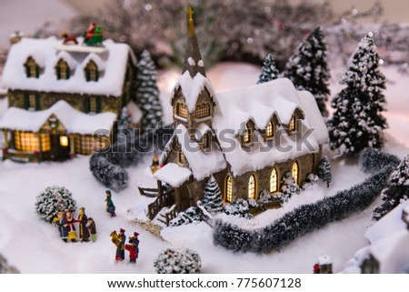Miniature Christmas village model church, in a snowy imitation  scene  with carolers in front of the church