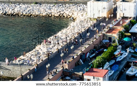 Aerial view of a detail of the city streets of Naples, Italy, from the top of  Castel dell'Ovo. Many people walk in the waterfront during a nice sunny day.