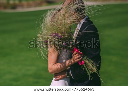 Newlyweds look at each other And smile. Wedding bouquet of the bride with feather grass and elements of rustic